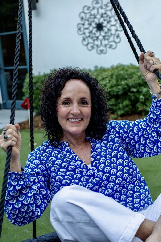 Julie James holistic health practitioner sitting on a swing outdoors